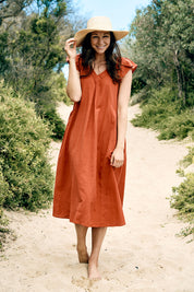 A model wearing the Vin colourNeck Maxi Dress - Guava (Red), from the front, showing the whole outfit