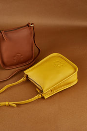 A model wearing the Small Leather Crossbody Bag in colour Mustard, from the front, showing the whole outfit