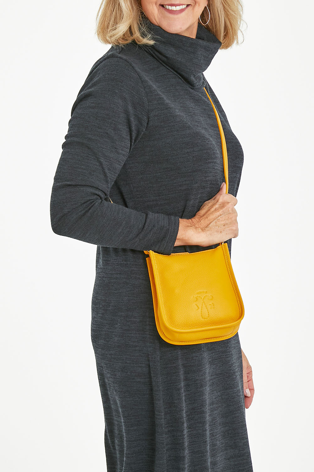 Model Sandy wearing size OneSize of the Small Leather Crossbody Bag in colour Mustard, from the front, cropped image