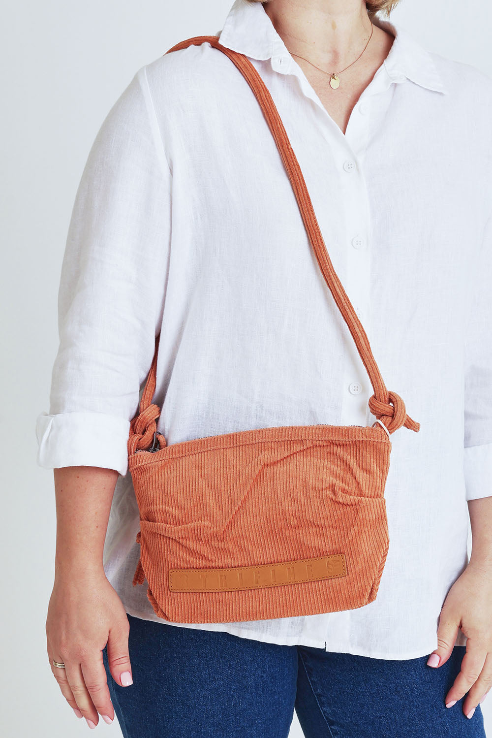 Model Steph wearing the Corduroy Crossbody Bag in colour Rust, from the front, cropped image