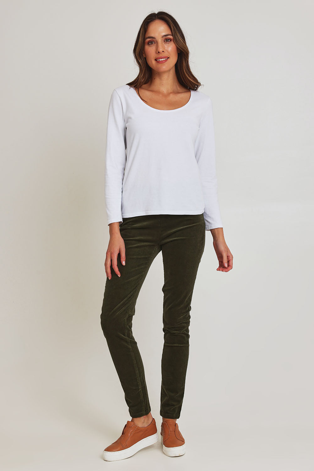 Model Madeline wearing size 10 of the Skinny Leg Cord Pull On Pant in colour Deepsage (Green), from the front, showing the whole outfit