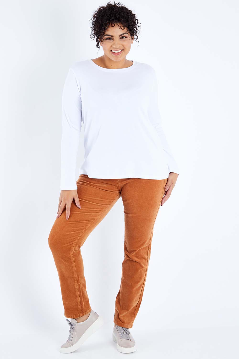 Model Sasha-Lee wearing size 16 of the Pin Cord Slim Pant in colour Copper, from the front, showing the whole outfit