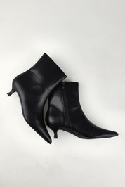 A model wearing size 37 of the Luca Kitten Heel Ankle Boot in colour Black (Black), from the front, showing the whole outfit