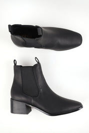 A model wearing size 37 of the Nas Ii Ankle Boot in colour Black (Black), from the front, showing the whole outfit