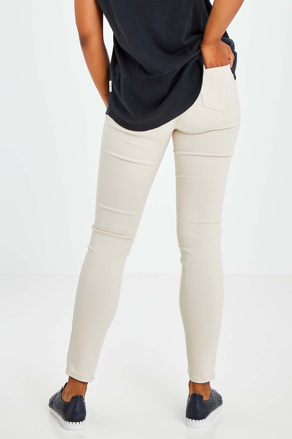 Model Olivia wearing size 10 of the Raven Skinny in colour Cream (White), from the back