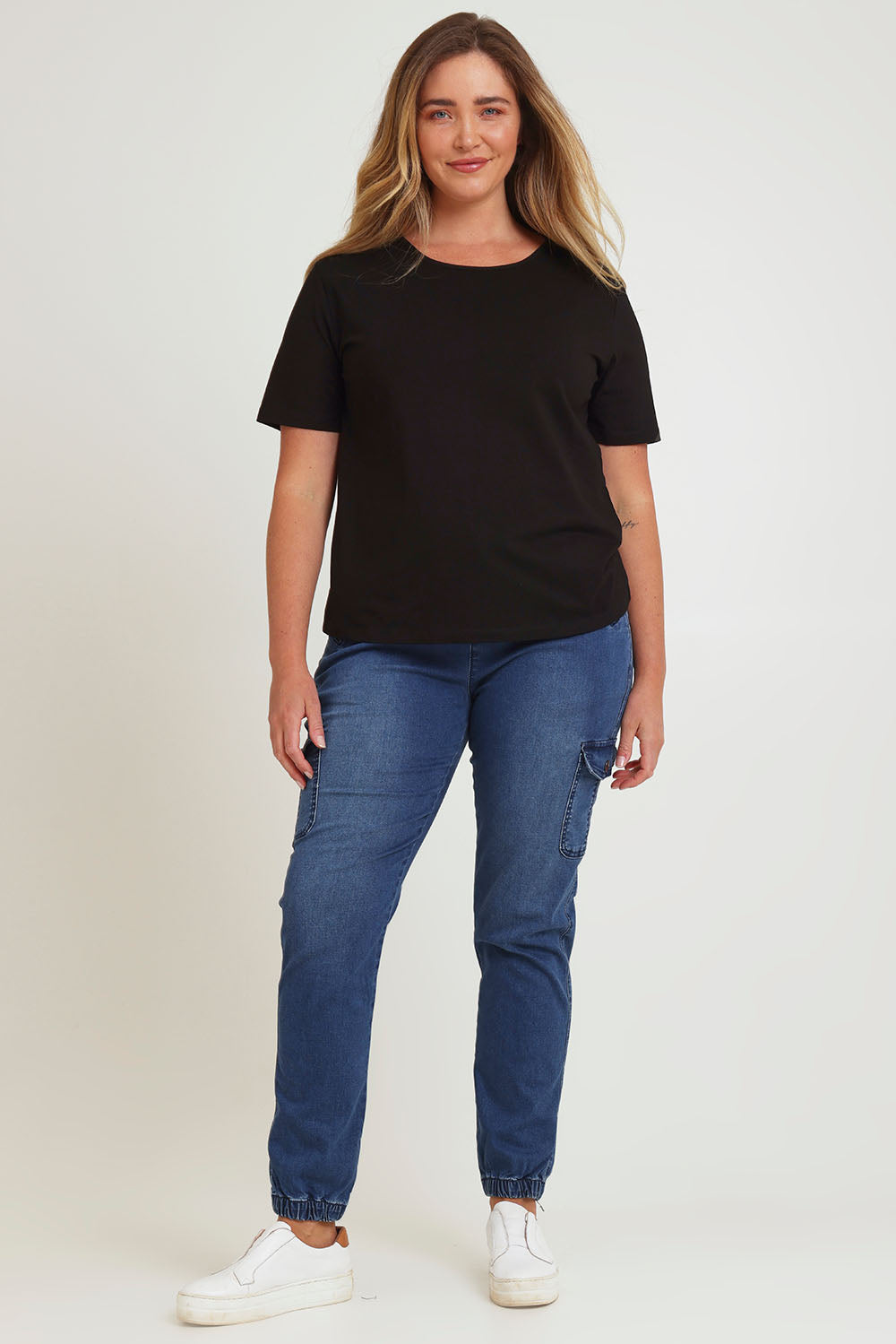 Model Chanel wearing size 16 of the Harlow Cargo Jogger in colour Darkdenim (Blue), from the front, showing the whole outfit