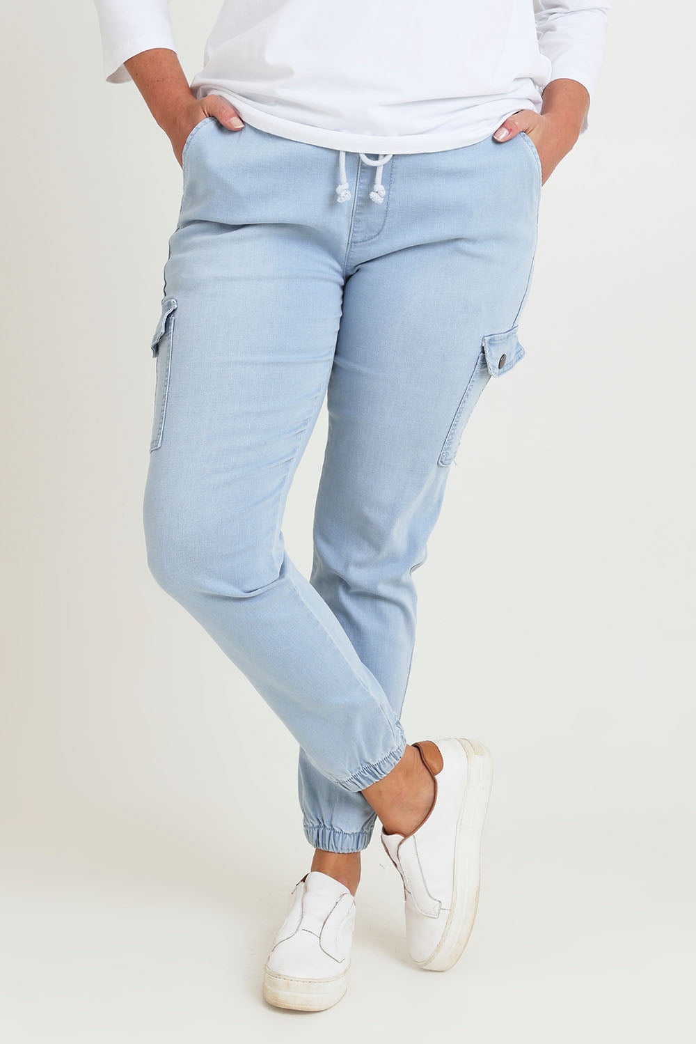 Model Chanel wearing size 16 of the Harlow Cargo Jogger in colour Lightdenim (Blue), from the front, cropped image