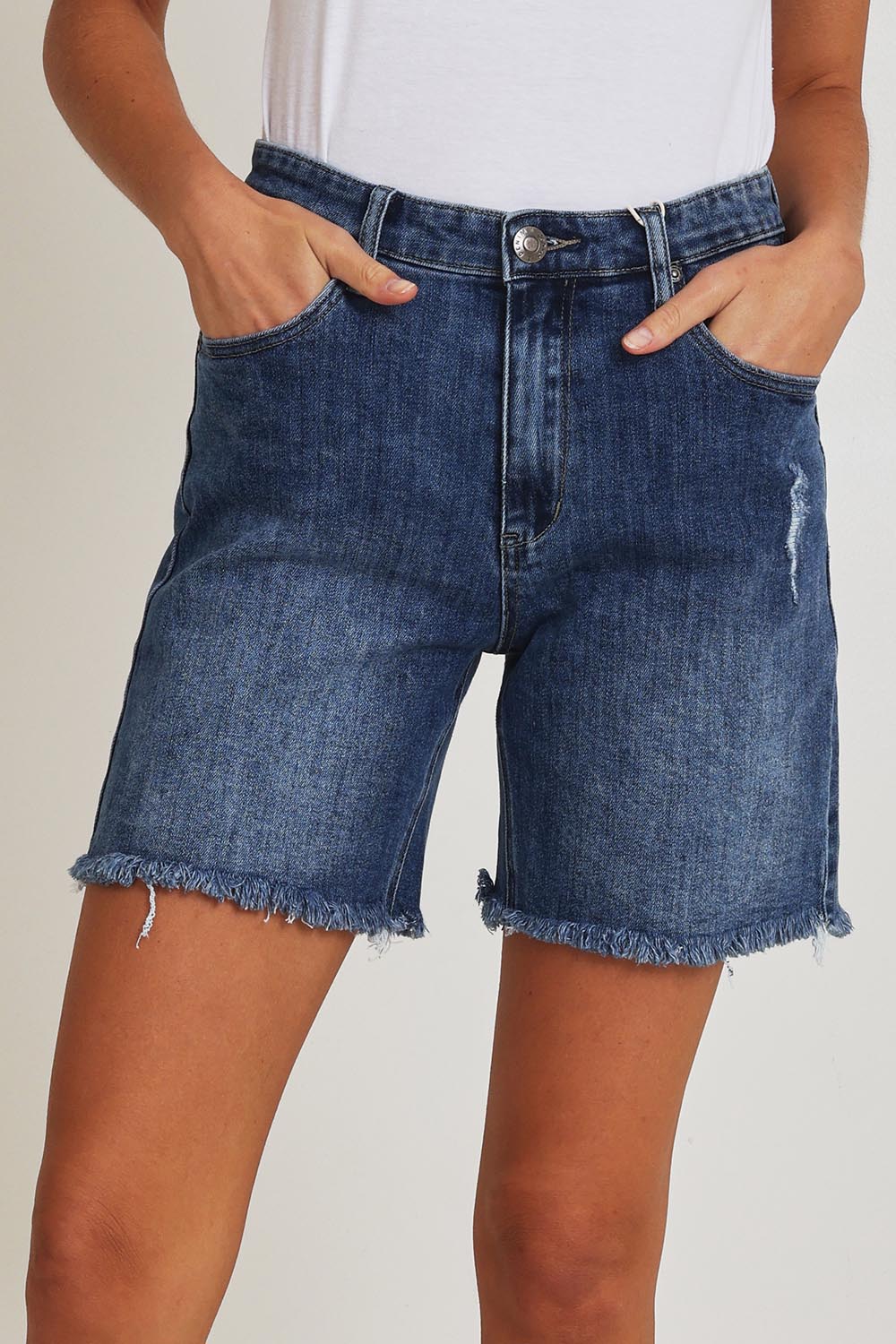 Model Madeline wearing size 10 of the Kerrie Frayed Hem Shorts in colour Dkdenim (Blue), from the front, cropped image