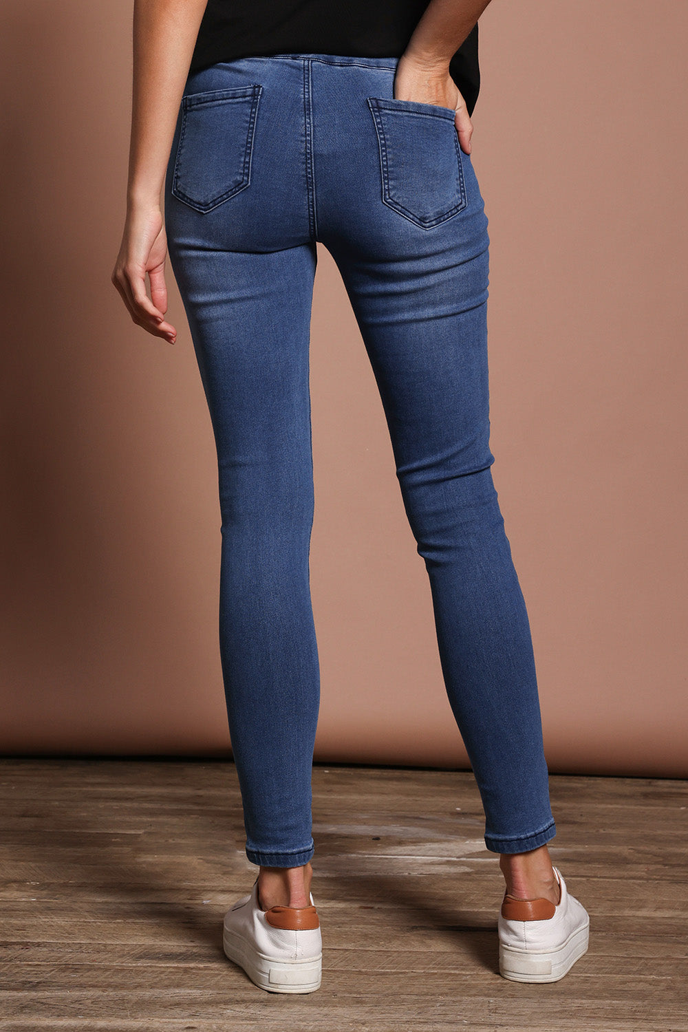 Model Madeline wearing size 9 of the Paige Pull On Jean in colour Midblue (Blue), from the back