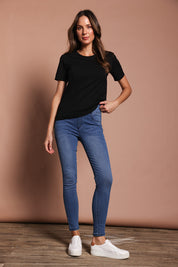 Model Madeline wearing size 9 of the Paige Pull On Jean in colour Midblue (Blue), from the front, showing the whole outfit