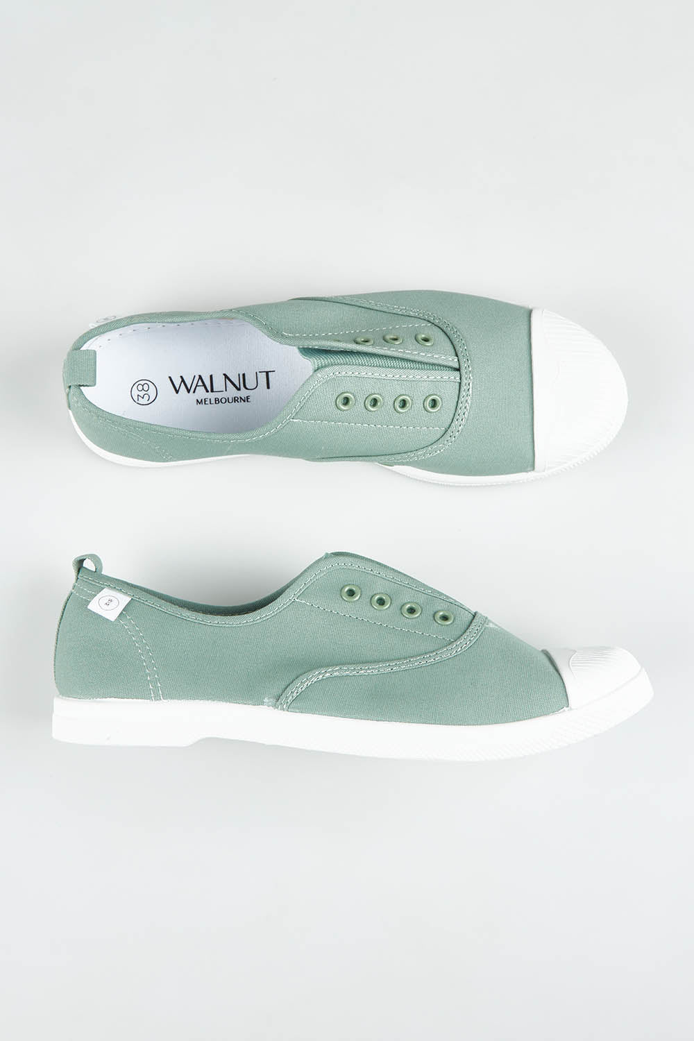 A model wearing size 37 of the Euro Plimsole in colour Sage (Green), from the front, showing the whole outfit