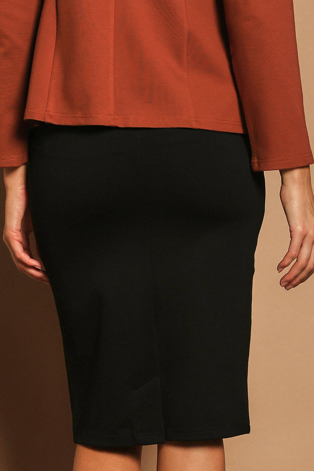 Model Madeline wearing size 10 of The Ponte Knee Length Pencil Skirt in colour Black (Black), from the back