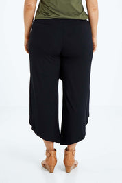 Model Laura wearing size L of the Crossover Bamboo Pant in colour Black (Black), from the back