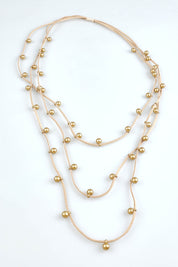 A model wearing the Emaline Multi Row Necklace in colour Gold (Metallics), from the front, showing the whole outfit